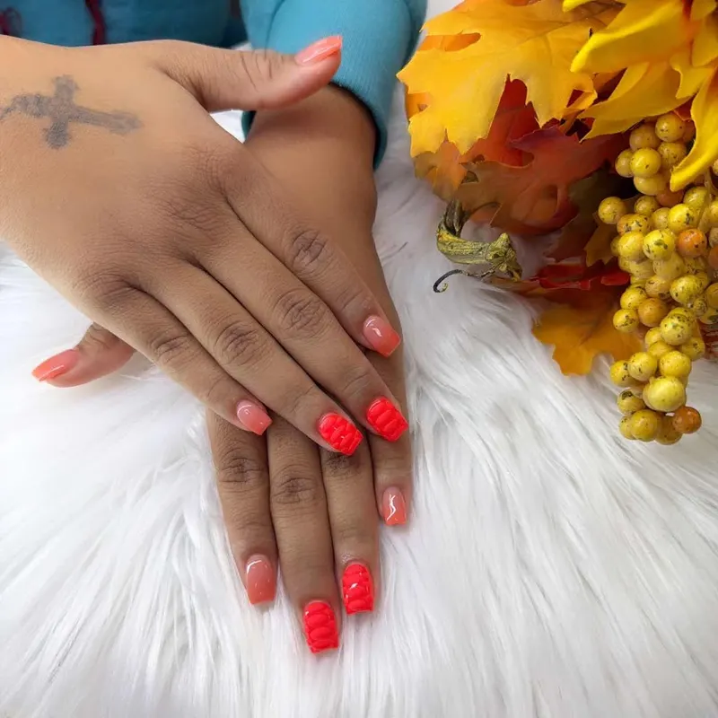 Warm coral nails styled with autumn flowers